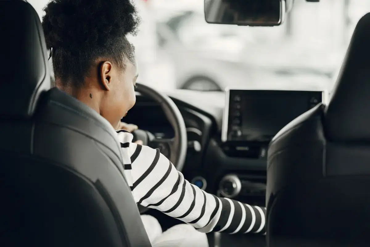 Jeune femme au volant d'une voiture, vue depuis la banquette arrière