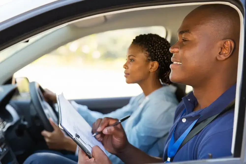 Élève au volant et moniteur prenant des notes pendant une leçon de conduite