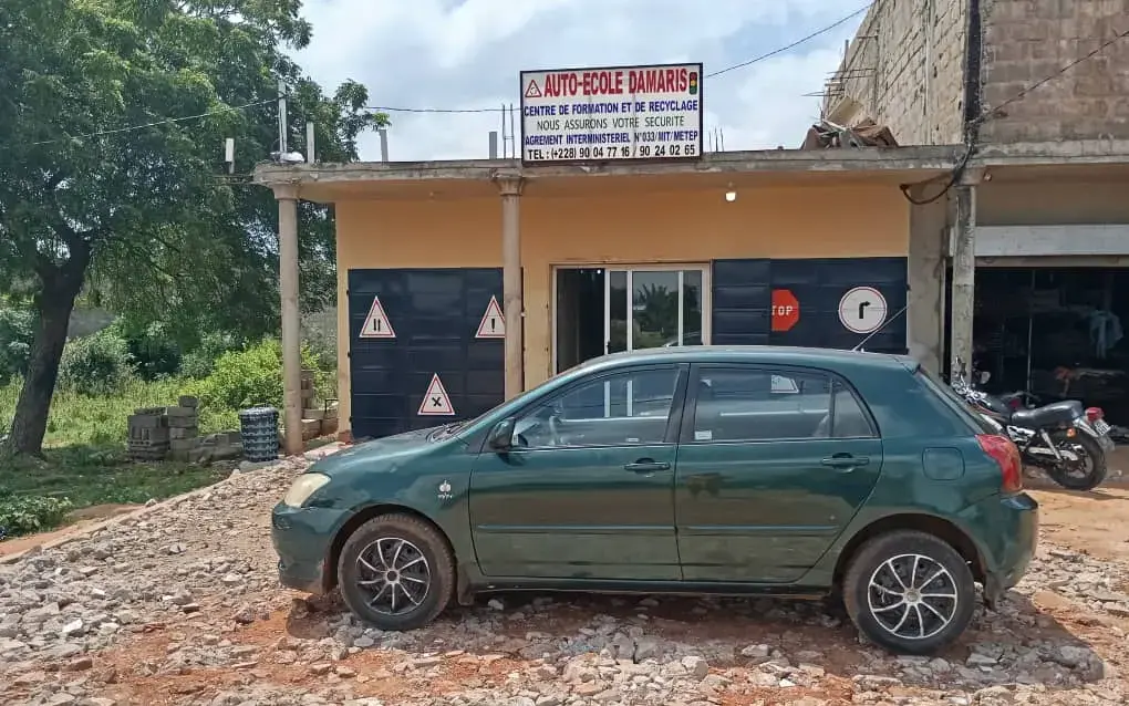Façade du siège Damaris à Djagblé-Klobatémé, avec une voiture d'apprentissage
